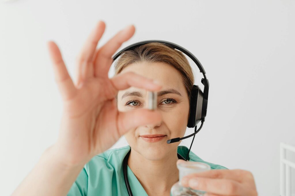 doctor wearing headphone holding a pill between her fingers